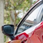 Person documenting vehicle damage after a car accident in Texas while taking notes for a police report