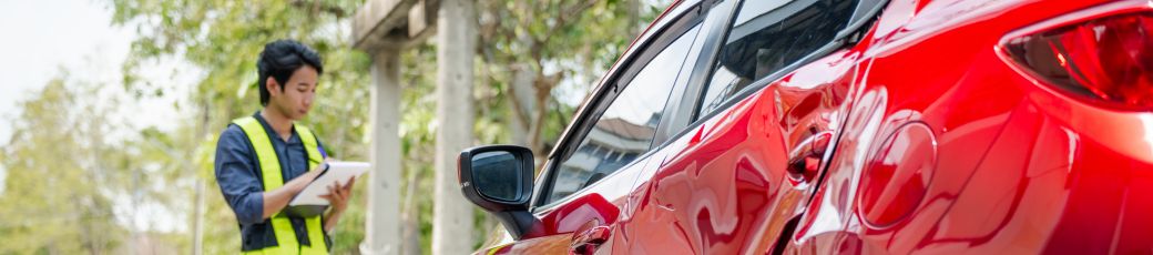 Person documenting vehicle damage after a car accident in Texas while taking notes for a police report