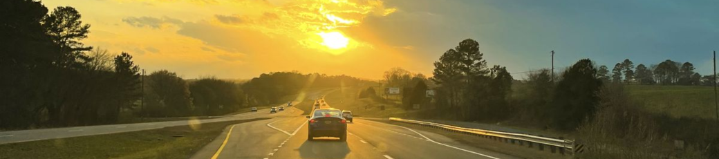 Vehicles driving on a highway at sunset during busy summer travel season in Texas