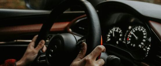Driver holding steering wheel while driving on a road in Texas during summer travel season