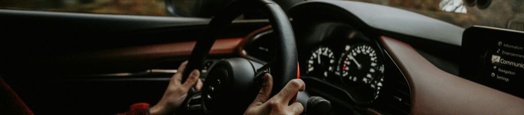 Driver holding steering wheel while driving on a road in Texas during summer travel season