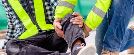 Construction worker receiving assistance after suffering a leg injury at a construction site.