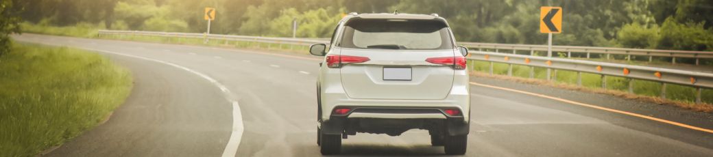 SUV driving on a curved roadway during warm summer weather in Texas.