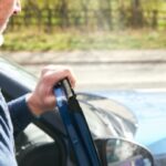 Man experiencing neck pain after a car accident while standing beside a damaged vehicle