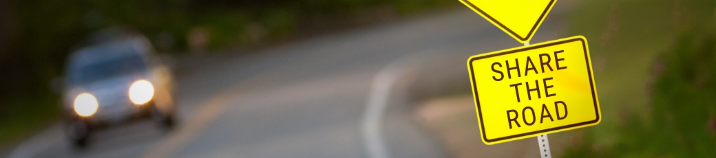 Share the Road sign beside a roadway reminding drivers in McAllen, Texas, to watch for cyclists and pedestrians during the busy summer season.