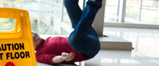 Person slipping on a wet floor next to a caution sign, illustrating a slip and fall accident that may result in a personal injury claim.