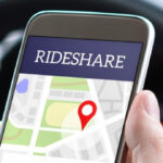 Rideshare driver holding a smartphone with a rideshare app open while driving