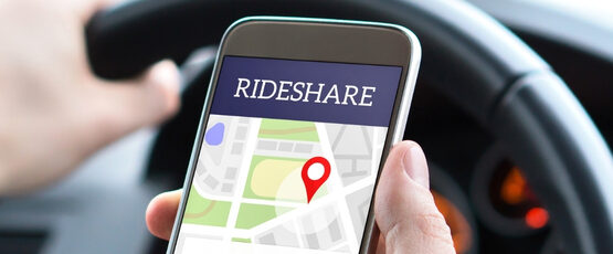 Rideshare driver holding a smartphone with a rideshare app open while driving