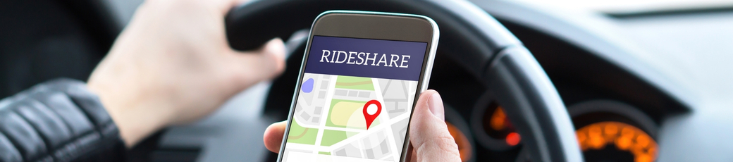 Rideshare driver holding a smartphone with a rideshare app open while driving