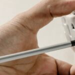 Person using a screwdriver to install an electrical outlet while working on home electrical wiring