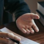 Personal injury lawyer reviewing legal documents with a client at a desk, with law books and scales of justice nearby.