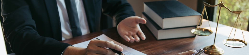 Personal injury lawyer reviewing legal documents with a client at a desk, with law books and scales of justice nearby.