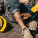 Injured construction worker receiving assistance from a coworker at a worksite.