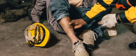 Injured construction worker receiving assistance from a coworker at a worksite.