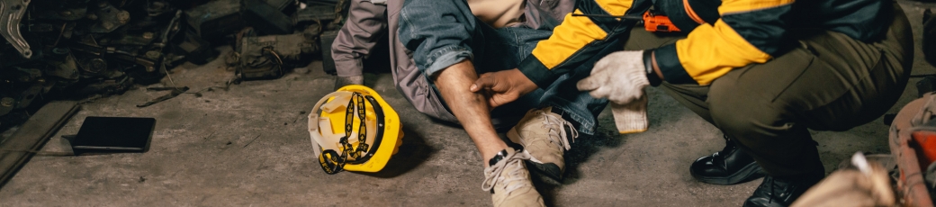 Injured construction worker receiving assistance from a coworker at a worksite.